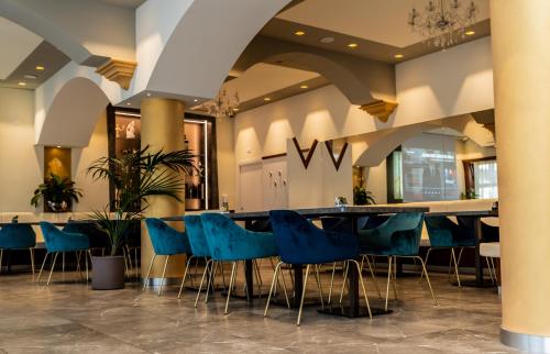 een lobby met een lange tafel en blauwe stoelen bij Hotel Shangri-La in Ala