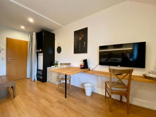 ein Wohnzimmer mit einem Tisch und einem Flachbild-TV in der Unterkunft Komfortables Doppelzimmer in Kehl Goldscheuer - 1A Guesthouse in Kehl am Rhein
