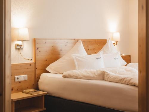 a bedroom with a bed with white sheets and pillows at alpina&more APARTMENTS I ZIMMER in Serfaus