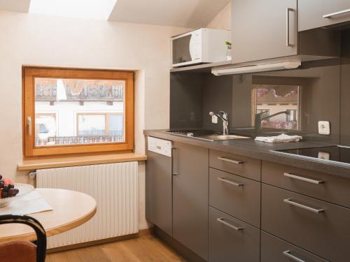 a kitchen with a sink and a table and a window at alpina&more APARTMENTS I ZIMMER in Serfaus
