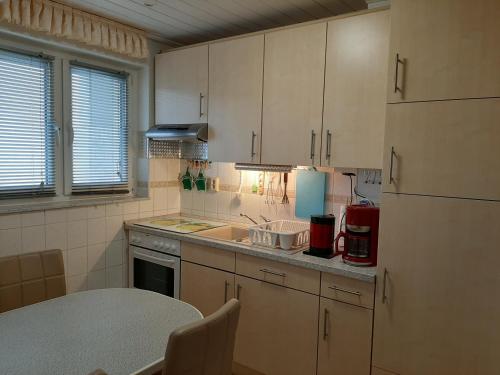 cocina con armarios blancos, fregadero y mesa en HomeSweetHome Free Parking Wifi Elevator Balcony, en Kassel