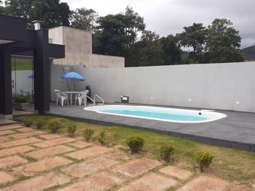 a swimming pool with a table and an umbrella at Recanto Silveira Minas in Capitólio