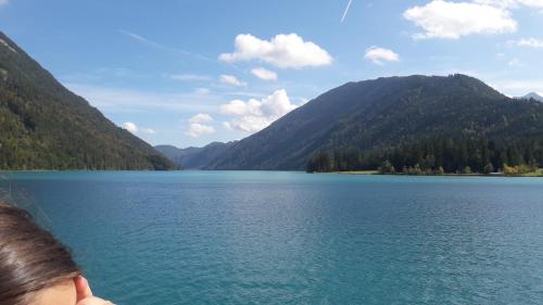 a woman looking at a lake in the mountains at Ferienhof Alte Post, Apartments in Weissbriach
