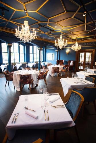 a restaurant with white tables and chairs and chandeliers at Royal Oak Hotel in Betws-y-coed
