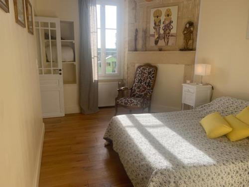 1 dormitorio con 1 cama, 1 silla y 1 ventana en Clos des oliviers, en Aubie-et-Espessas