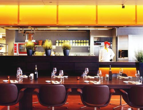 a restaurant with a table and a chef in the kitchen at Radisson Blu Hotel, Lucerne in Luzern
