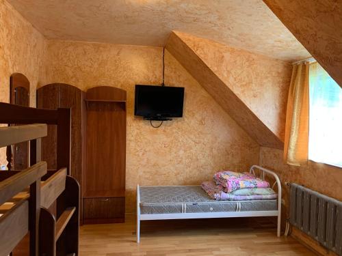 um pequeno quarto com uma cama e uma televisão na parede em Садыба над Рикою em Berezovo