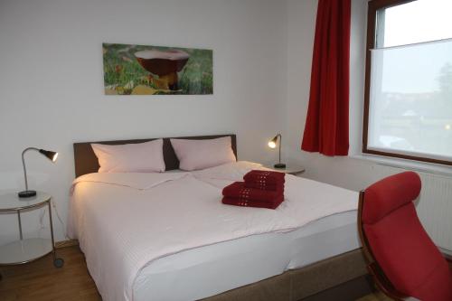ein Schlafzimmer mit einem weißen Bett und einem roten Stuhl in der Unterkunft FAMOS Schlafen in Warburg