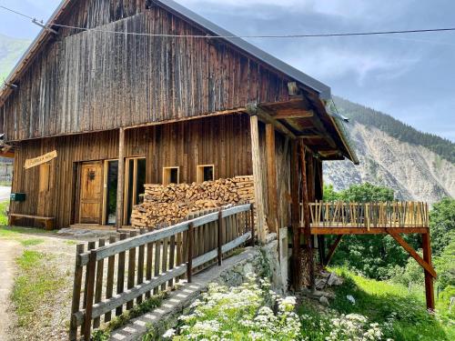 a wooden barn with a pile of wood outside at Authentique grange savoyarde in Albiez-Montrond