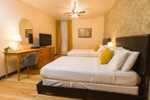 a bedroom with two beds and a desk and a television at Hotel Dorion in Montréal