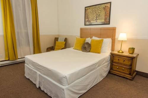 a bedroom with a large white bed with yellow pillows at Hotel Dorion in Montréal