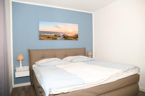 a bedroom with a white bed with a painting above it at Zum Meer in Damp