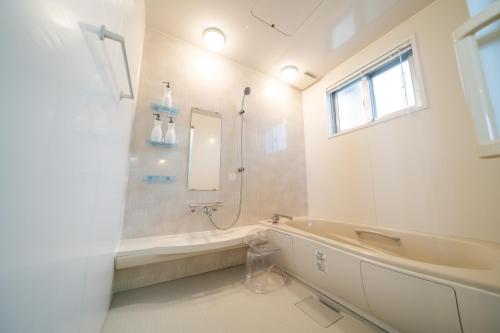a white bathroom with a tub and a sink at SEA VIEW HOUSE KIRA KIRA HINANO in Nanjo