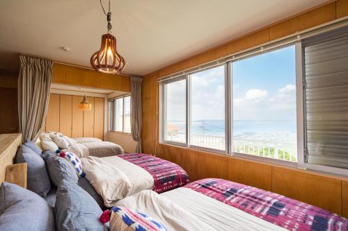 two beds in a room with a large window at SEA VIEW HOUSE KIRA KIRA HINANO in Nanjo