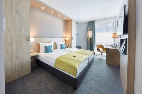 a hotel room with a bed and a desk at GHOTEL hotel & living Bochum in Bochum