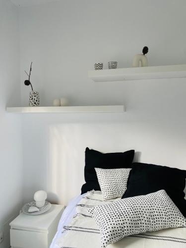 a white bedroom with a bed with black and white pillows at Alcarria , Casa del Agua in Albalate de Zorita