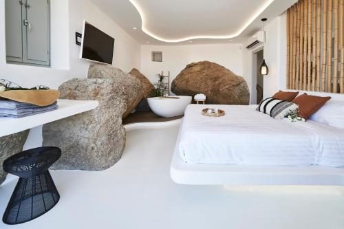 a bedroom with a bed and some large rocks at Teal Rock Mykonos in Ano Mera