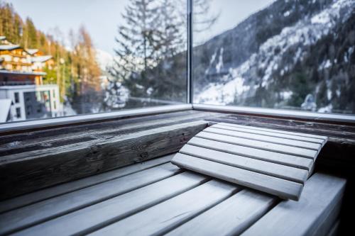 a bench in front of a window with a snowy mountain at Hotel Karl Schranz in Sankt Anton am Arlberg