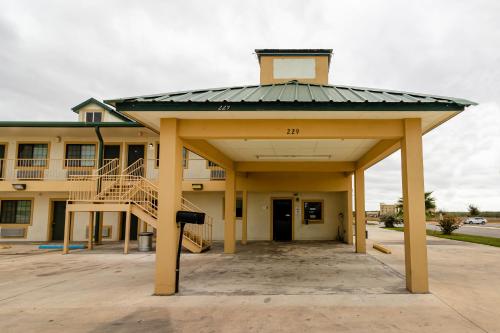 um grande edifício com um telhado em cima em OYO Hotel Pearsall I-35 East em Pearsall