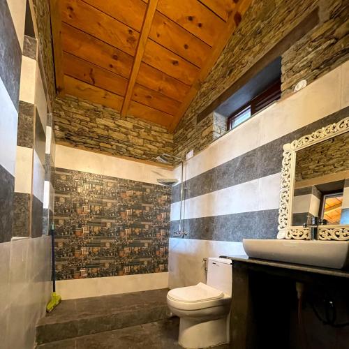 a bathroom with a toilet and a sink at Meraki Huts in Pauri