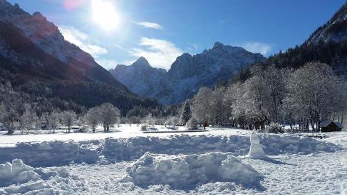 a pile of snow in a field with mountains at Rooms Barovc by the Lake Jasna in Kranjska Gora