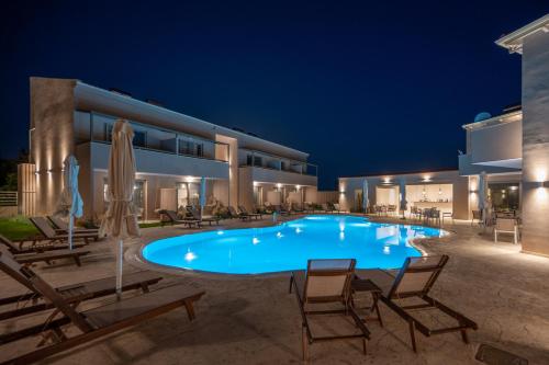 a swimming pool in front of a building at night at Scarabeo Suites & Villas Parga in Parga