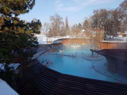 a large swimming pool with people in the water at Hét Vezér Apartmanhotel in Komárom