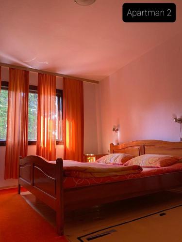 a bedroom with a large bed with orange curtains at Apartmani Jarevac in Bajina Bašta