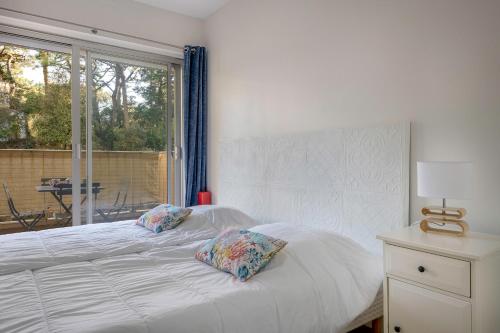 - une chambre avec un lit blanc avec deux oreillers et une fenêtre dans l'établissement Appartement avec double terrasse - 170m de la plage, à La Baule