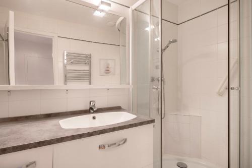 une salle de bain blanche avec un lavabo et une douche dans l'établissement Appartement avec double terrasse - 170m de la plage, à La Baule