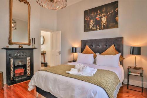 a bedroom with a large bed and a fireplace at Beaumont Cottages 2 by CTHA in Cape Town