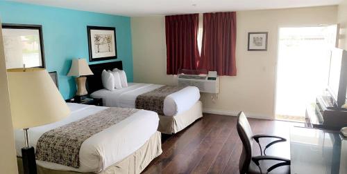 a hotel room with two beds and a table and chairs at Howard Johnson by Wyndham Buena Park in Buena Park
