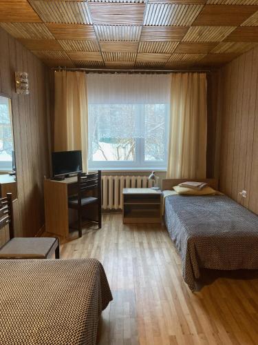 1 dormitorio con 2 camas, escritorio y ventana en Helge Guest Apartment en Valga