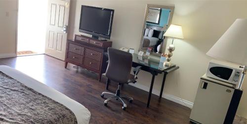 a bedroom with a desk with a chair and a television at Howard Johnson by Wyndham Buena Park in Buena Park