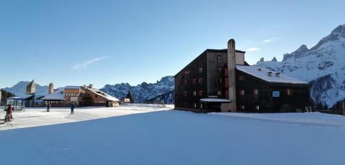 a building in the snow next to a mountain at CASA LOLA in Falcade