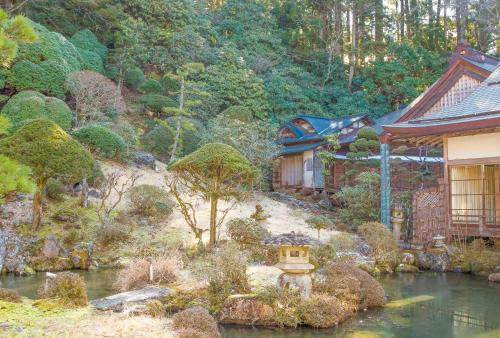 an asian garden with a house and a pond at 高野山 宿坊 普門院 -Koyasan Shukubo Fumonin- in Koyasan