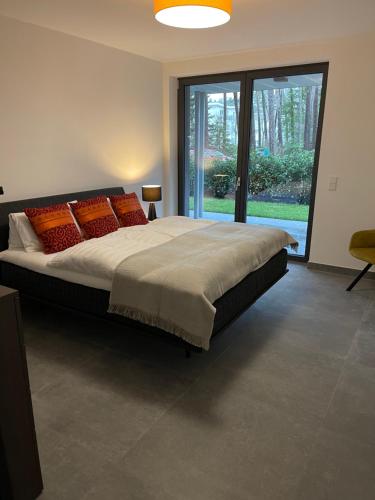 ein Schlafzimmer mit einem großen Bett mit orangefarbenen Kissen in der Unterkunft Basalt Lodge am Lehnitzsee in Oranienburg