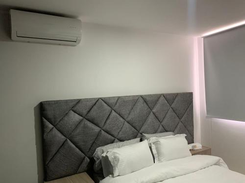 Bett mit grauem Kopfteil in einem Zimmer in der Unterkunft Bello Apartamento , Ubicado en el mejor sector in Cúcuta