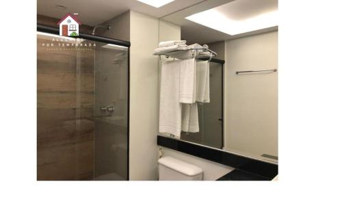 um banheiro com chuveiro, vaso sanitário e espelho em Aluga-se por temporada em Vitória