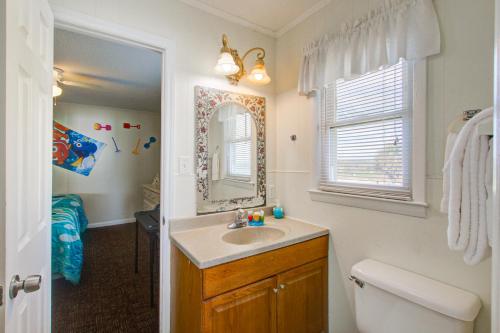 a bathroom with a sink and a toilet and a mirror at Charisma in Holden Beach