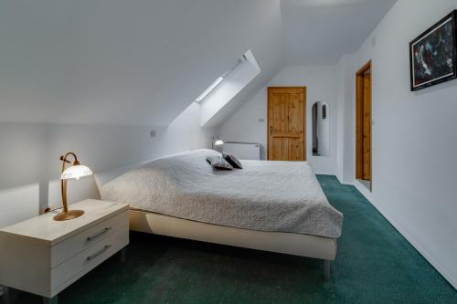 a white bedroom with a bed and a night stand at Sobe "Ela" in Fužine