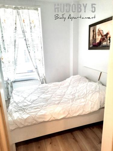 a bedroom with a bed with white sheets and a window at Apartament Biały CHUDOBY 5 Gliwice in Gliwice