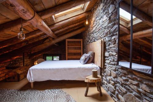 a bedroom with a bed in a stone wall at JAT MOUNTAIN HOUSES - Casa Pairal Jarca - dúplex - a 1 km de Canillo in Canillo