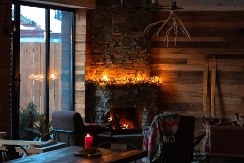a fireplace in a restaurant with a table and a candle at Capra Hotel Kazbegi in Stepantsminda
