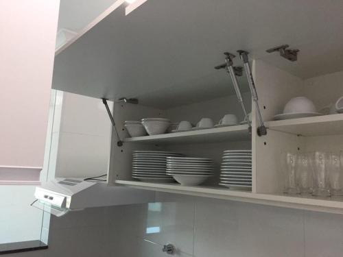 a white cabinet with plates and dishes in it at Residencial Green Village in Ubatuba