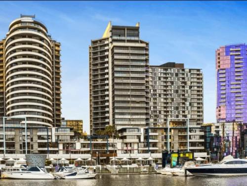 a group of tall buildings with boats in the water at Lovely waterfront condo with swimming pool and gym in the heart of Docklands in Melbourne