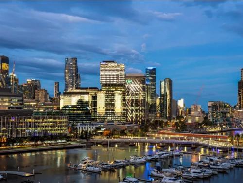 a city skyline at night with boats in a harbor at Lovely waterfront condo with swimming pool and gym in the heart of Docklands in Melbourne