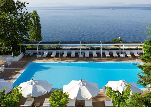 a swimming pool with umbrellas and chairs and the ocean at Atrium Hotel in Agia Paraskevi