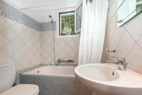 a bathroom with a sink and a tub and a toilet at Villa Katina in Nisakion