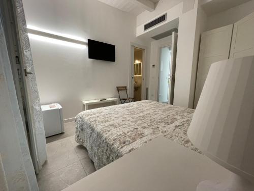 a white bedroom with a bed and a tv on the wall at Azzurramare Bed & Breakfast in Grottammare